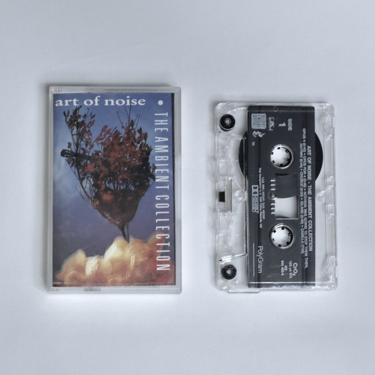 Art of Noise – The Ambient Collection cassette tape in a clear case, cover art of a tree emerging from clouds, shown alongside the cassette