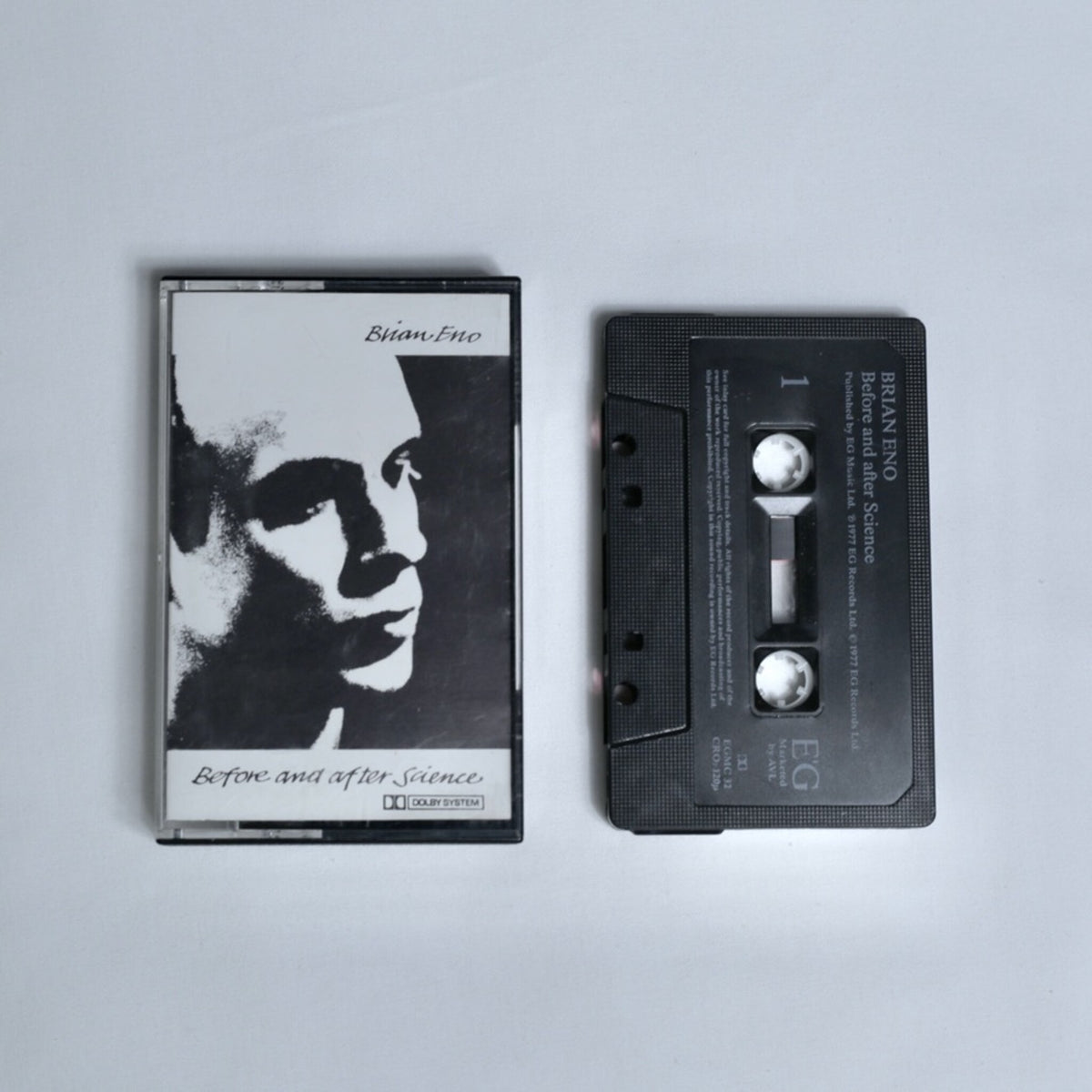 Brian Eno – Before and After Science cassette tape, black and white portrait cover art with Dolby System branding, shown alongside the cassette