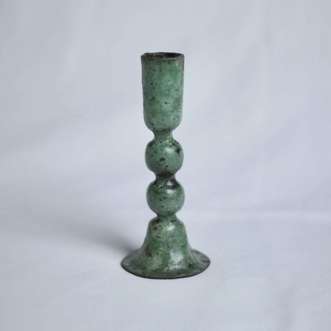 Large verdigris candle holder on a light grey background