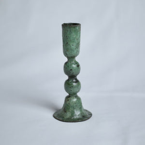 Large verdigris candle holder on a light grey background