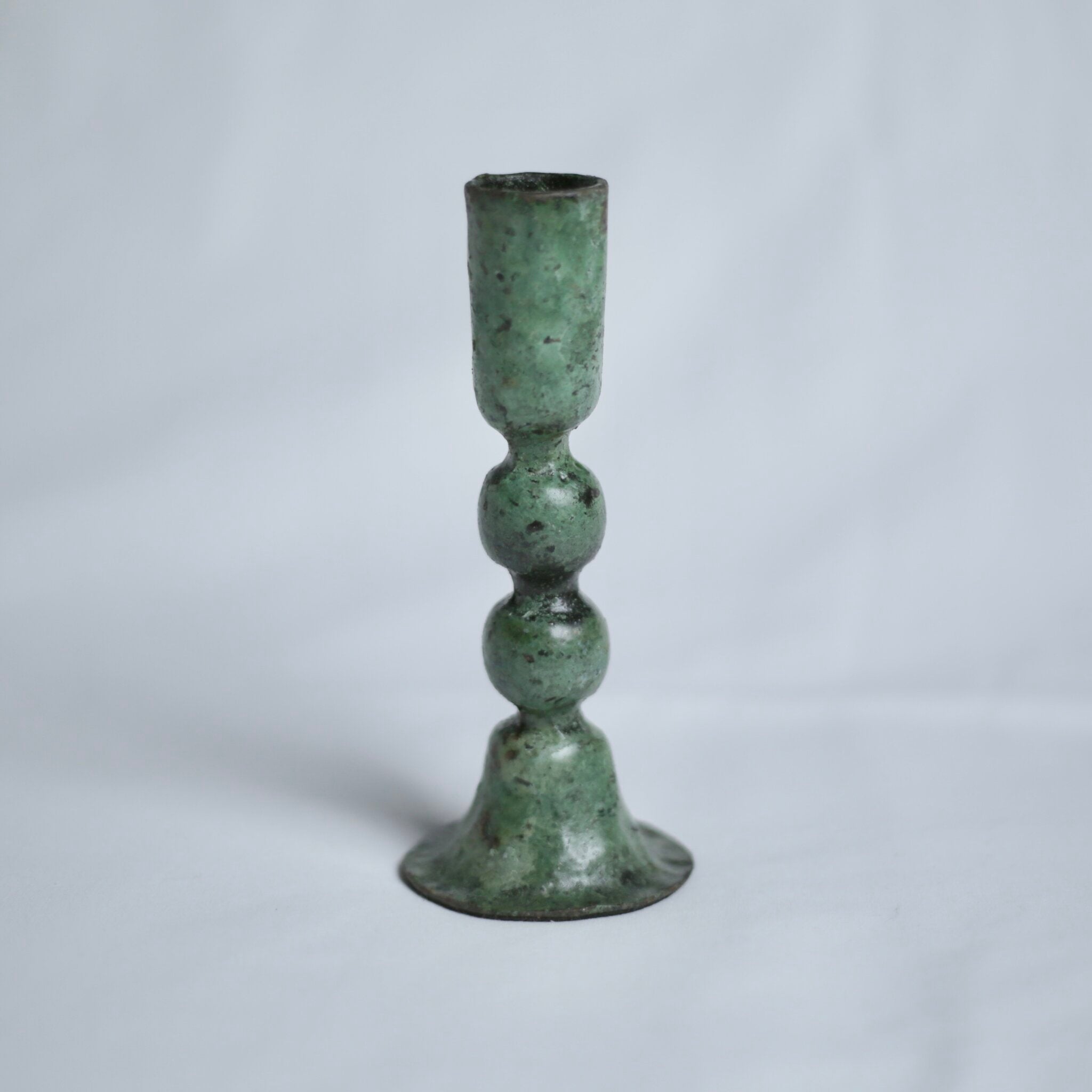 Large verdigris candle holder on a light grey background