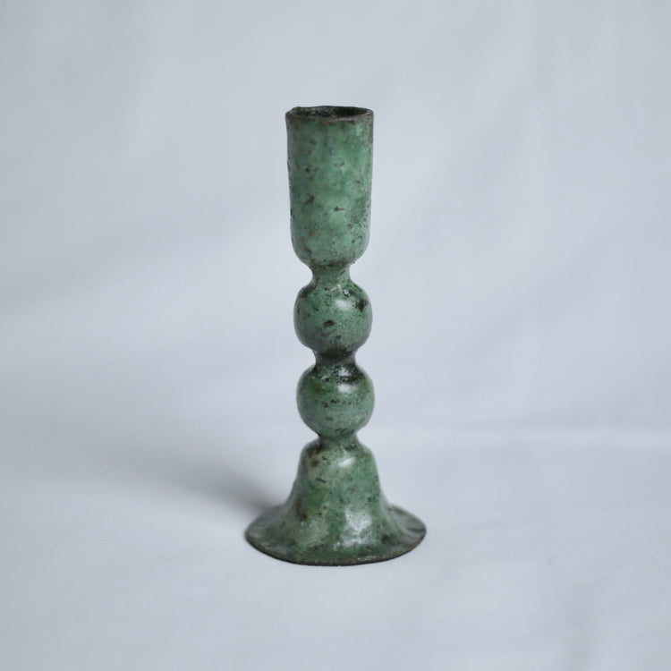 Large verdigris candle holder on a light grey background