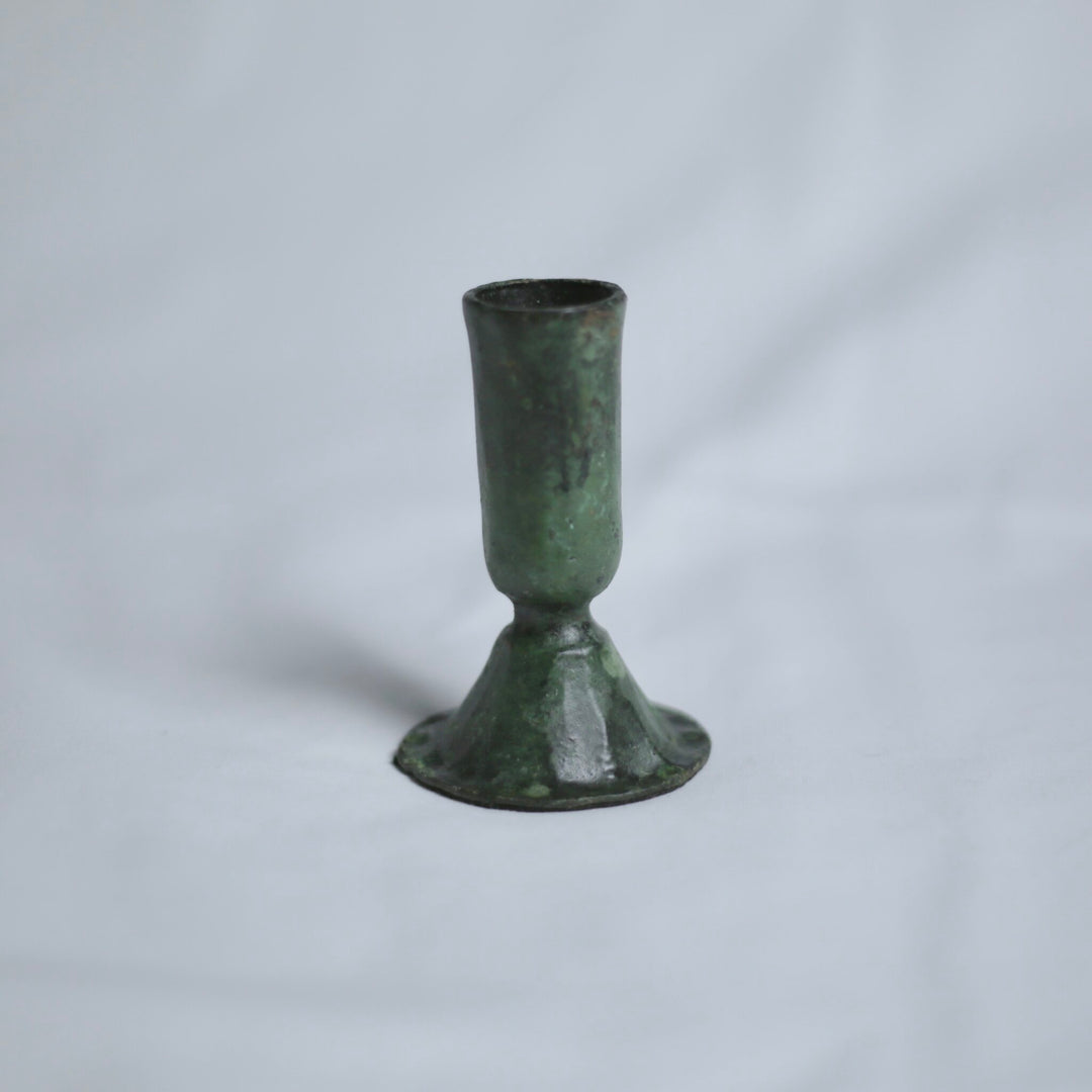 Verdigris candle holder on a light grey background