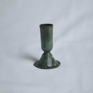 Verdigris candle holder on a light grey background