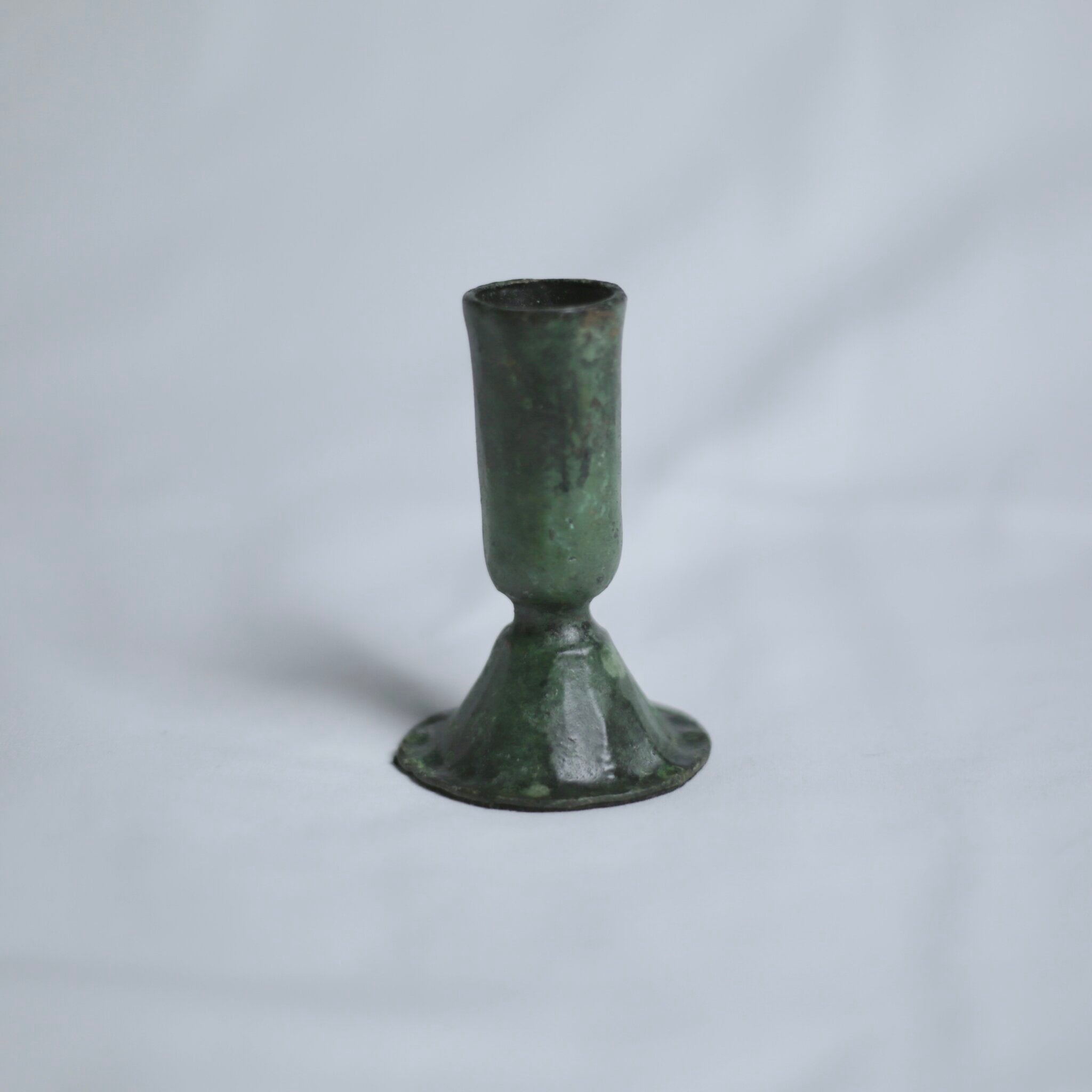 Verdigris candle holder on a light grey background