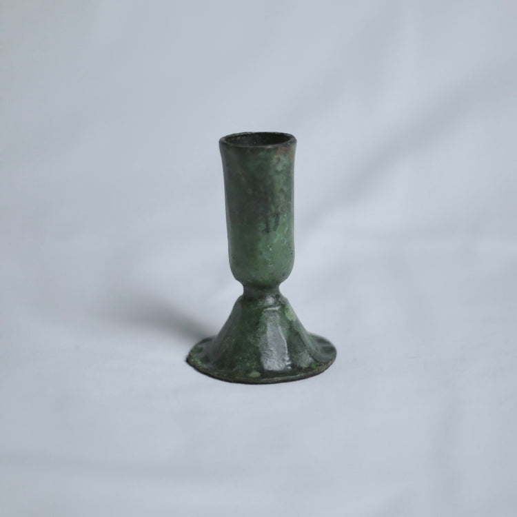 Verdigris candle holder on a light grey background