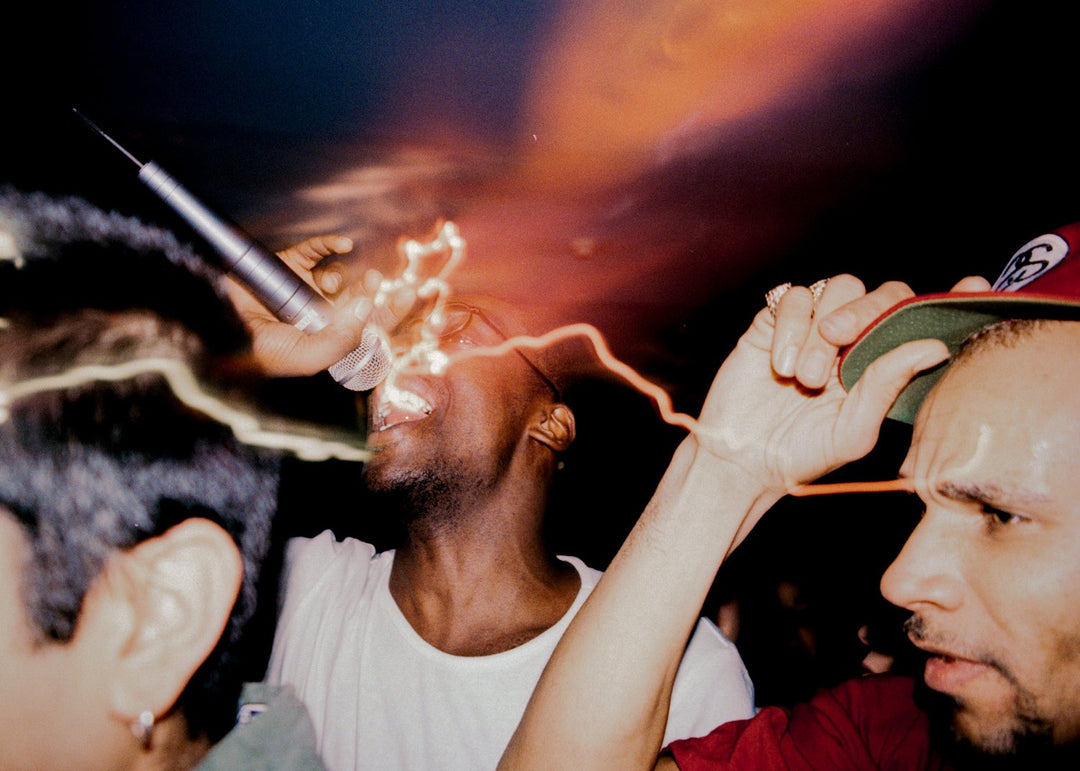 A man and Goldie with a microphone against a dark background