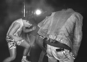 Two people one playing air guitar on wearing a denim jacket