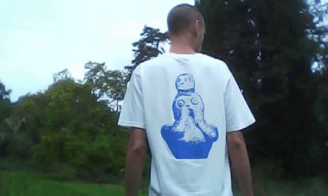 Person wearing a white t-shirt with a blue graphic design outdoors