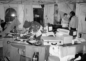 Electronic music jam in a warehouse space with people in the background.