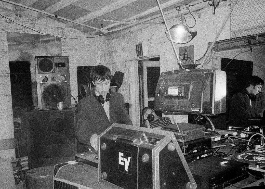 Person jamming with electronic equipment in a room with exposed brick walls.