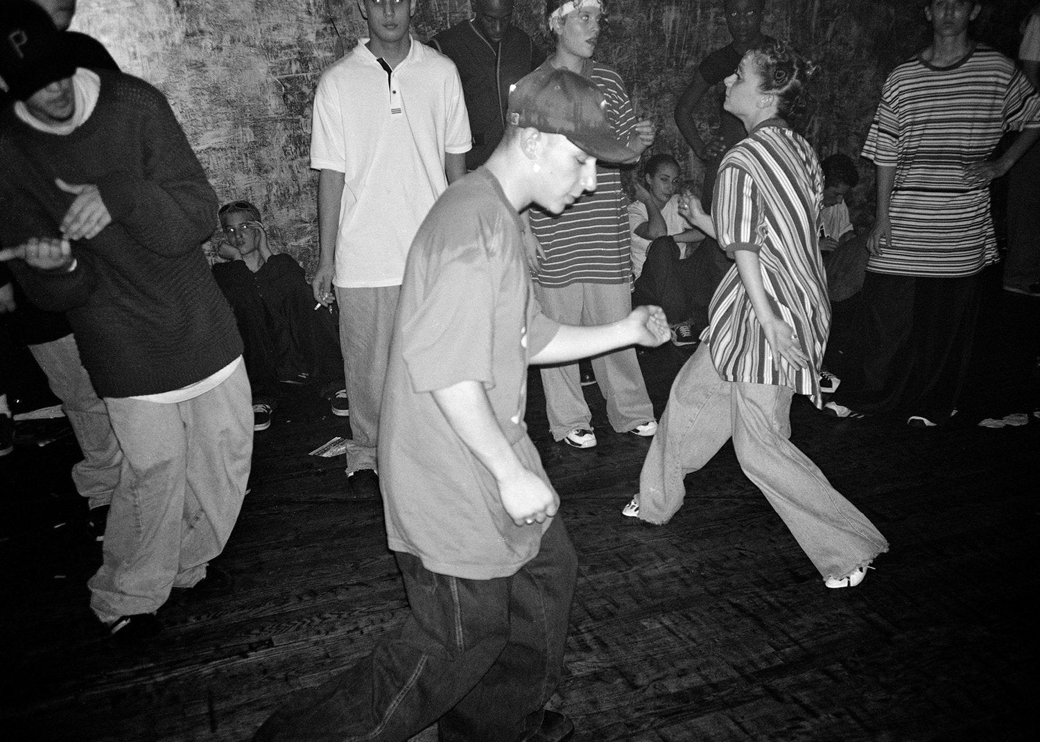 Black and white photo of a group of people dancing in a dark room.