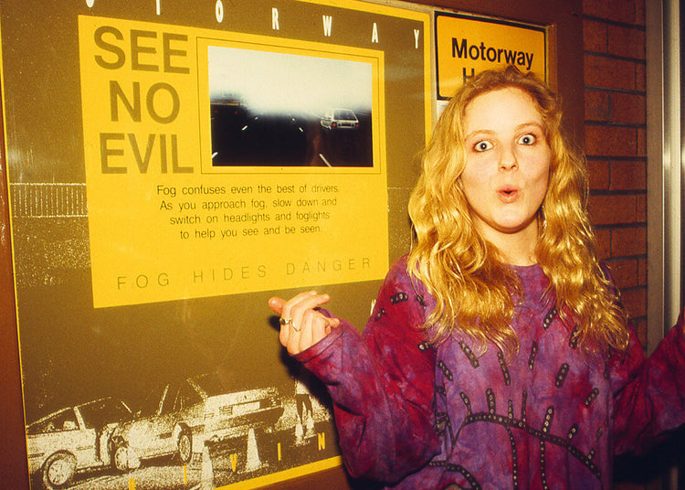 Woman pointing at a 'See No Evil' poster on a motorway.