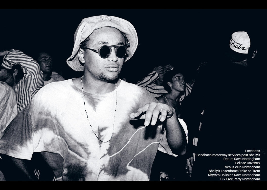 Black and white photo of a person wearing sunglasses and a hat on a dark background
