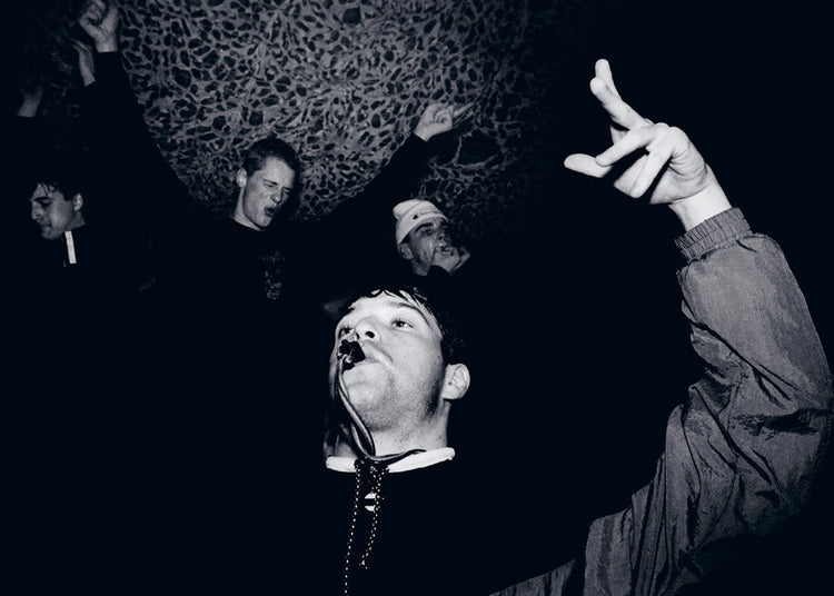 Black and white photo of a group of people with one blowing a whistle making a hand gesture.