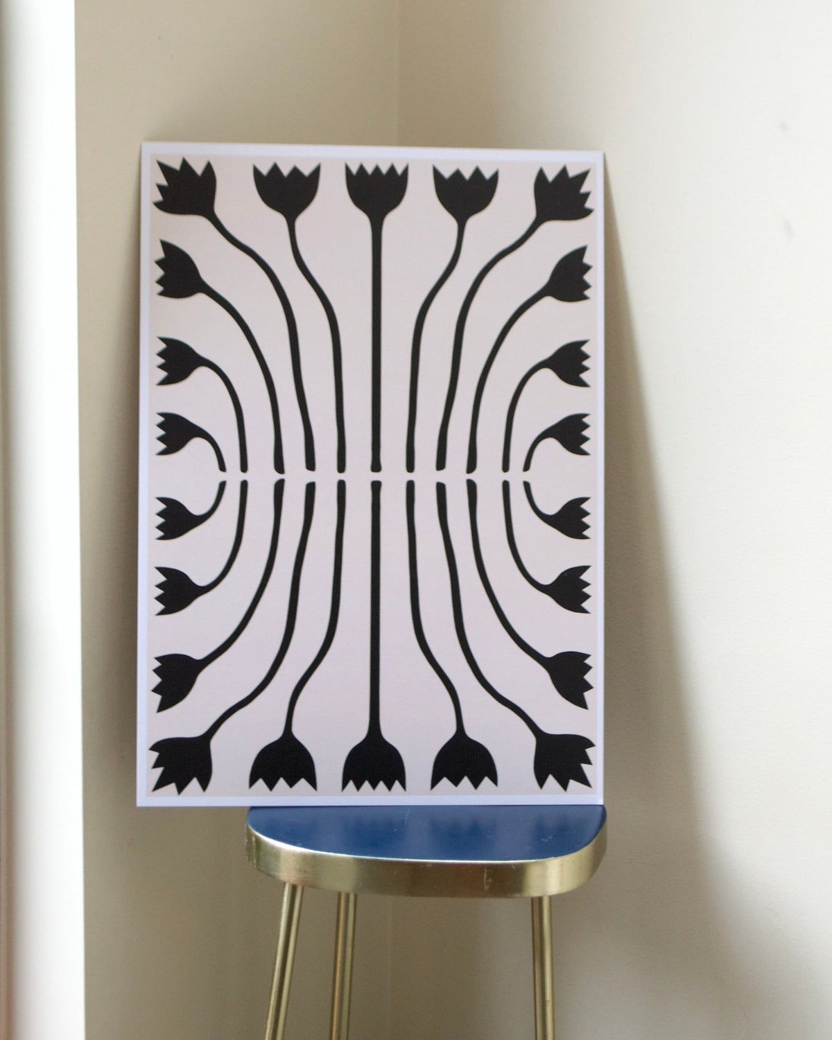 Tilly Worth Tulips A3 print in situ leaning on a brass and blue stool on a greige wall