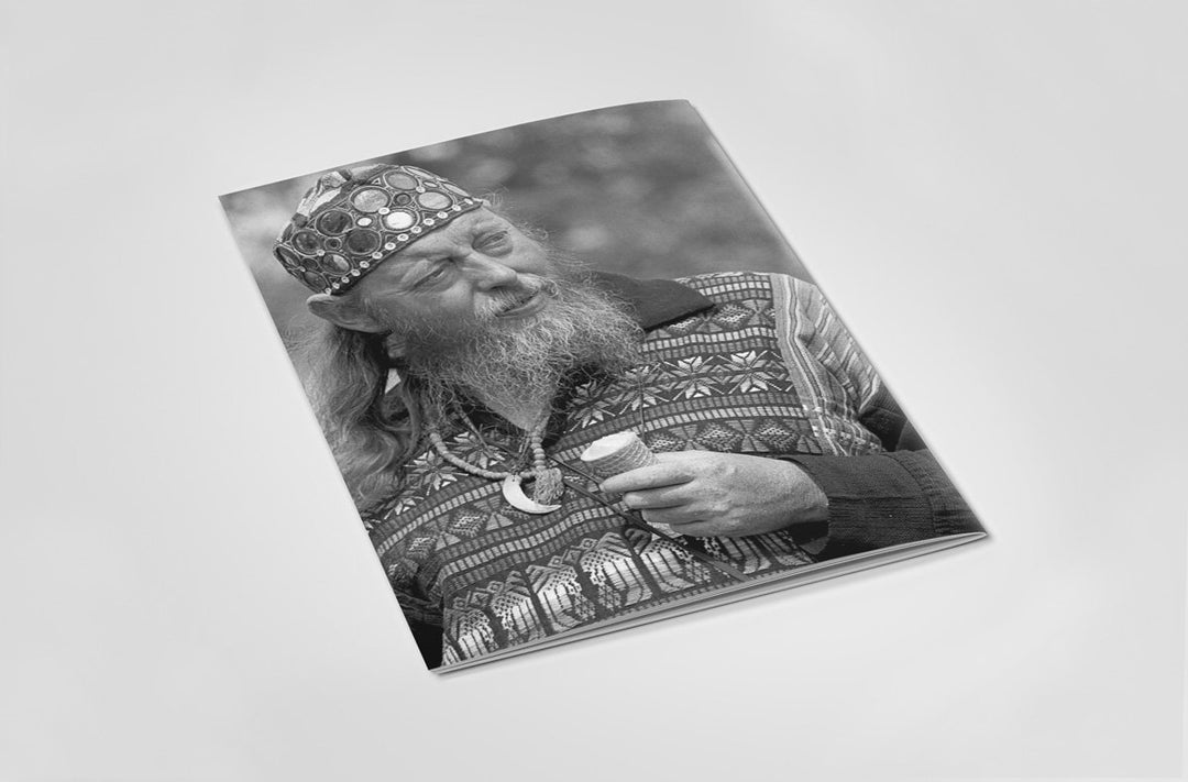 Back cover of book with a black and white photo of a man wearing pagan attire with patterned outfit and hat.