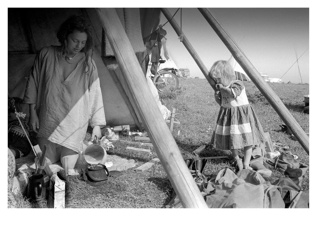 Black and white photograph of a woman and child in a tent outdoors.
