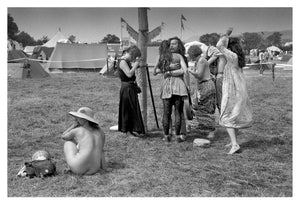 Black and white photograph of people at a festival with tents and open fields in the background